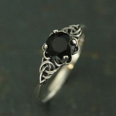 a black diamond sits on top of a silver ring with filigrees around it