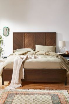 a large bed sitting on top of a wooden floor next to a lamp and rug