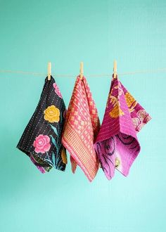 three towels hanging on a clothes line against a blue wall, with one folded and the other unzipped