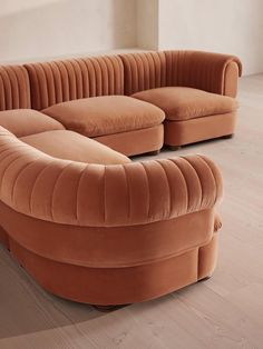 a curved couch sitting on top of a hard wood floor