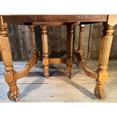 an old wooden table with four legs and two turned down ends, on a wood floor