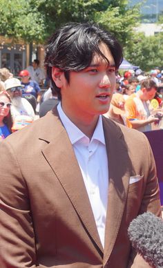 a man in a brown suit and white shirt is talking to someone with a microphone