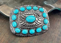 This buckle has a western style design in silver metal. It fits with a metal bar and pin (for a snap on belt). It is decorated with a synthetic turquoise pieces. Quality guaranteed, picture does not do this buckle justice! Would make a stand out addition to your belt.To find the perfect snap on belt for your buckle check our store!Measurements/Sizing * The buckle measures 3 1/4" x 2 1/4" and it fits up to a 1 1/2'' strap. Southwestern Turquoise Concho Belt Buckles, Blue Concho Western Belt Buckles, Western Style Blue Concho Belt Buckles, Adjustable Turquoise Western Belt Buckles, Turquoise Belt, Turquoise Western, Western Belt Buckles, Western Belt, Western Design