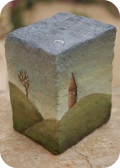 a stone block with an image of a tree and a house on it sitting on top of a rock