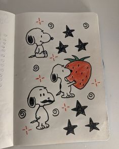 an open book with drawings of dogs, stars and a strawberry on the page in it