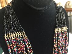 "Multi-color bead statement necklace with a tribal African flair. Lots of different shapes and colors, including a few tiny shells. About 18\" long, hangs about 4\" deep on your chest. Also, please take a look at my storefront at: https://www.etsy.com/shop/FabFinds42?ref=seller-platform-mcnav I have a wide selection of one-of-a-kind items, from clothing and toys to home decor and gift items, and I add new things almost every day." Multicolor Bib Necklaces With Dangling Round Beads, Multicolor Bib Necklace With Dangling Round Beads, Multicolor Bib Necklace With Round Dangling Beads, Bohemian Bib Necklaces With Colorful Round Beads, Bohemian Multi-strand Heishi Beads Necklace, Artisan Beaded Necklace With Black Beads, Multi-strand Wooden Beaded Necklaces For Festivals, Bohemian Bib Necklaces For Jewelry Making With Black Beads, Bohemian Heishi Beaded Necklace With Polished Beads