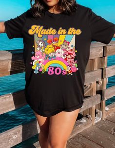 Step into a time machine of memories with our "Born in the 80s Nostalgia Retro Blast Tee." This vintage-inspired shirt is a vibrant tribute to the iconic era, featuring beloved characters like Strawberry Shortcake and her whimsical friends. Crafted from soft, comfortable fabric, this tee not only celebrates the spirit of the 80s but also offers a cozy fit for everyday wear. The lively design showcases a medley of colorful characters, bringing a burst of nostalgia to your wardrobe. Whether you're reliving your own 80s adventures or introducing the magic to a new generation, this tee is a perfect way to make a statement. Embrace the charm, fun, and enduring appeal of the 80s with every step you take in this delightful piece. Join us in celebrating the era that left an indelible mark on pop c Retro Character Print T-shirt For Fan Conventions, Retro T-shirt With Screen Print For Fan Conventions, Vintage Graphic T-shirt For Fan Conventions, Vintage Screen Print T-shirt For Fan Conventions, Retro Graphic Print T-shirt For Fan Conventions, Vintage Graphic Print T-shirt For Fan Conventions, Retro Screen Print Tops For Fan Conventions, Retro Crew Neck T-shirt With Character Print, Vintage Tops With Character Print For Fan Conventions