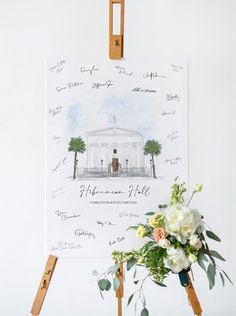 an easel with flowers in front of a white building