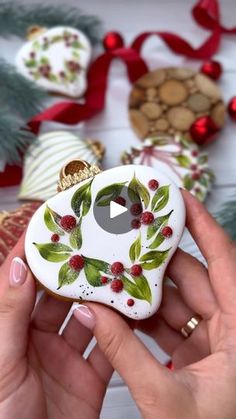 a person holding a small ceramic ornament in their hand with christmas decorations around it