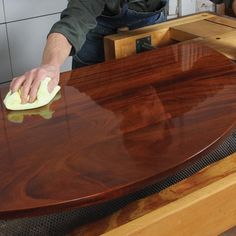 a person is cleaning a wooden table with a cloth