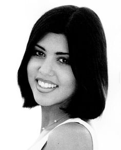 a black and white photo of a woman with short hair smiling at the camera while wearing a tank top