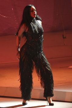 a woman in a black feathered dress on stage