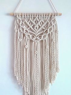 a macrame wall hanging on a white wall