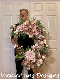 a woman standing in front of a door holding a wreath