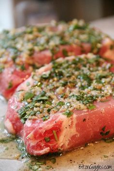 two pieces of raw meat with herbs on top