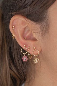 a close up of a person's ear wearing gold earrings with flowers on them