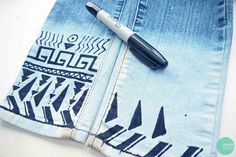 a pen sitting on top of a pair of blue jean pants with black and white designs