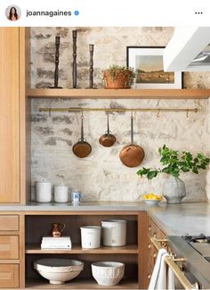 a kitchen with pots and pans hanging on the wall next to a stove top oven