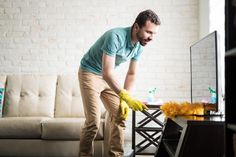 a man is cleaning the floor in his living room with yellow gloves and sponges