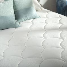 a close up view of a mattress with two pillows on the bottom and one pillow on the side