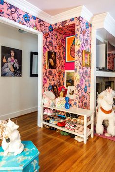 a living room filled with lots of furniture and wallpaper covered in pink flowers on the walls