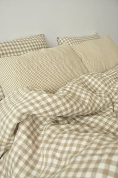 an unmade bed with brown and white checkered sheets