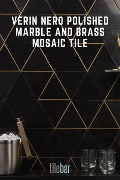 there is a black tiled wall with gold trim and glass vases on the counter