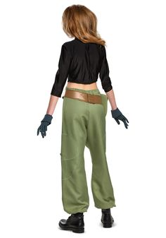 a woman in green pants and black shirt standing with her back to the camera, wearing gloves