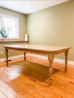 a wooden table sitting on top of a hard wood floor next to a white vase