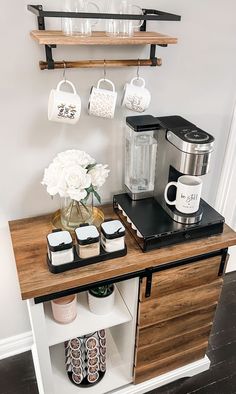 a coffee bar with cups and mugs on it next to a wall mounted shelf