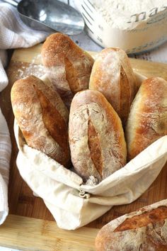 several loaves of bread in a basket on a cutting board