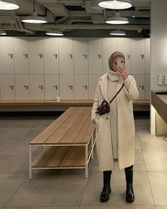 a woman is taking a selfie in the locker room with her cell phone up to her ear