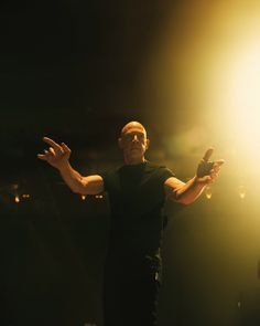 a man standing in the dark with his arms outstretched and hands out to the side