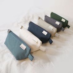 four different colored bags sitting on top of a white sheet