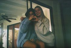 two women are posing for the camera in front of a mirror and one has her arm around another woman's neck