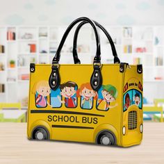 a yellow school bus purse with children's pictures on the front and side, sitting on a wooden table