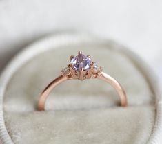 a pink diamond ring sitting on top of a white velvet covered cushioned seat in a box