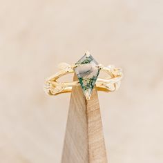 a green and white ring sitting on top of a wooden stand with a stone in the middle