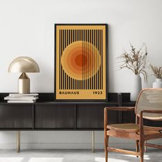 an orange and yellow poster hangs on the wall next to a chair in a white room