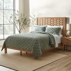 a bed in a bedroom with a green comforter and pillows on top of it