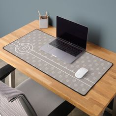 a laptop computer sitting on top of a wooden desk next to a mouse pad and chair