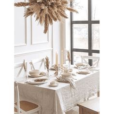 a dining room table set with dishes and place settings in front of a large window