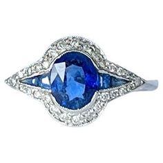 This unusual cluster ring holds sapphires and diamonds around the edges. The sapphire is bright blue in colour. The sapphire total is 1.15 carat and the diamonds total 30pts. Modelled in 18carat white gold. Ring Size: P 1/2 or 7 3/4 Cluster Dimensions: 17x11mm Weight: 3g