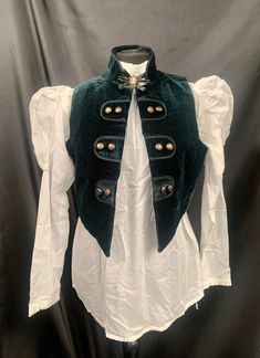 Steampunk Vest Gothic medieval pirate This comes with the following 3 items:- 1 Bottle green velvet waistcoat fully lined with rustic buttons. This is an open fronted waistcoat which does not button up , making it flexible sizing.please check photo for exact measurements . 2 .Off white blouse with mutton puff sleeves. This buttons up at the back.Uk 10 to 14 fits upto a 36 chest. Please note this voile blouse is see through .  3 . Pretty cameo brooch with diamanté . Thank you for looking Vintage Winter Costume Vest, Vintage Winter Vest For Costume, Velvet Waistcoat, Steampunk Vest, Off White Blouse, Corset Steampunk, Medieval Cosplay, Mode Steampunk, Craft Things