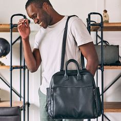 a man standing in front of shelves holding a black bag