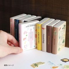 a hand is reaching for an open book on a table with other books in front of it