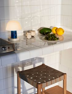 a small wooden stool in front of a counter with food on it and a plate