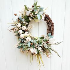 a wreath with white flowers and greenery hangs on the wall next to a door