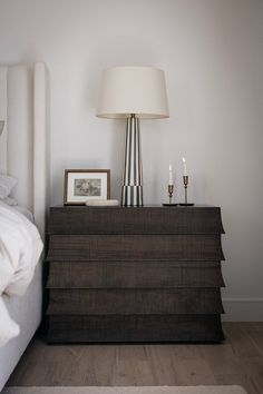 a lamp on top of a dresser next to a bed