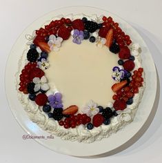 a cake decorated with berries and flowers on a plate